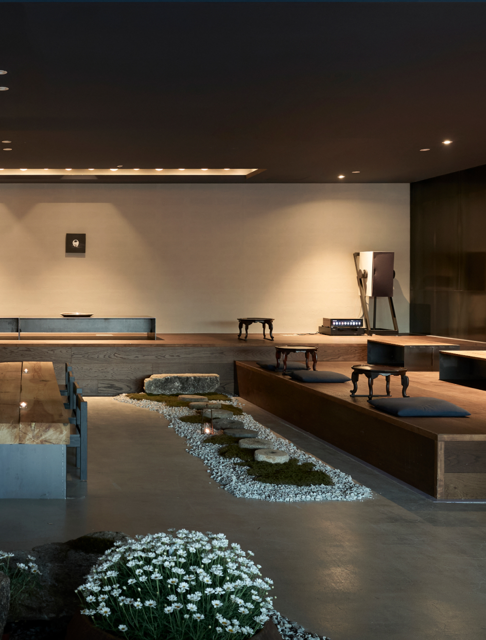 Floor-seating lounge with small tables and cushions beside the moss garden