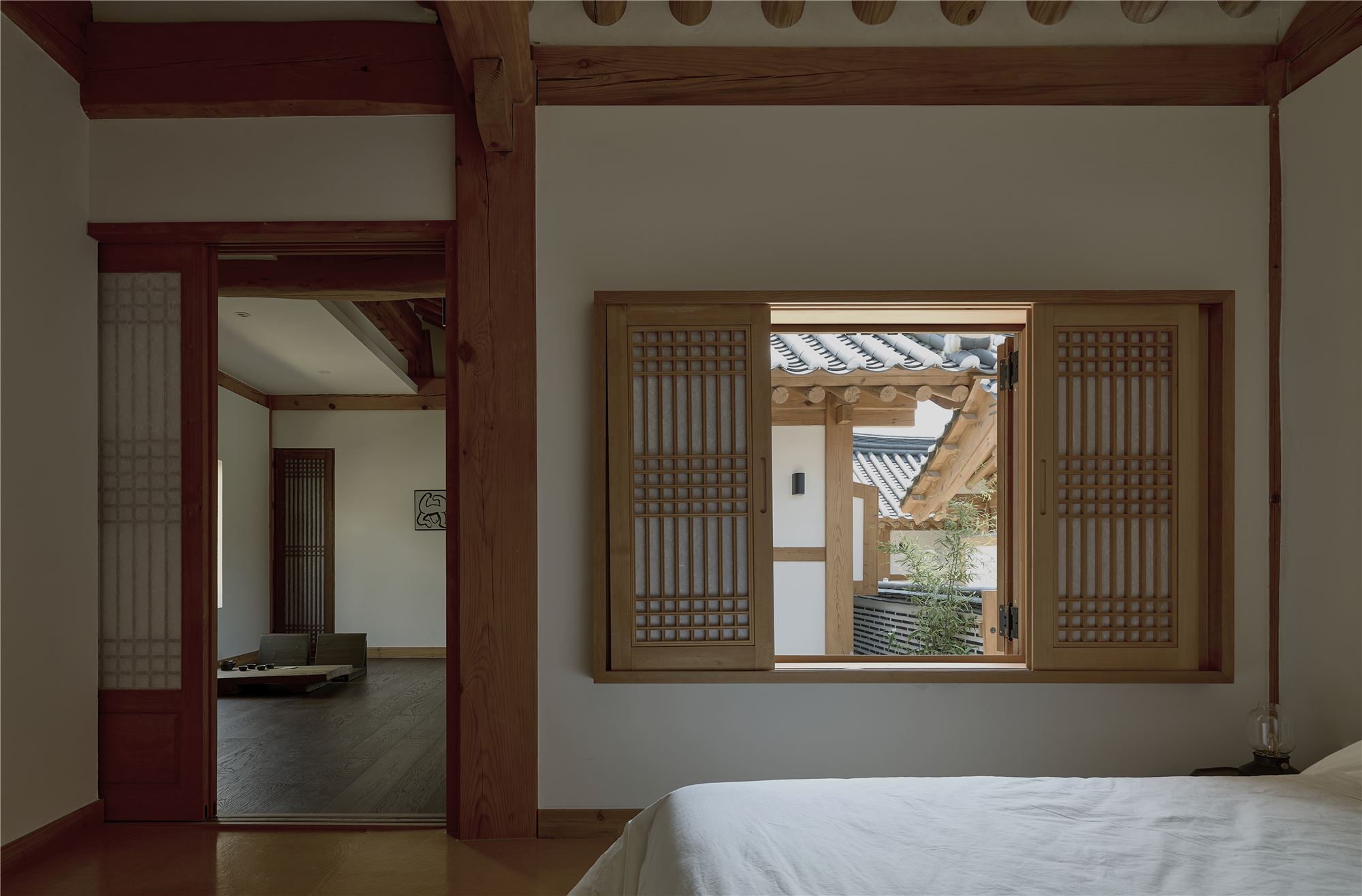 A bedroom looking out to tiled roofs and bamboo